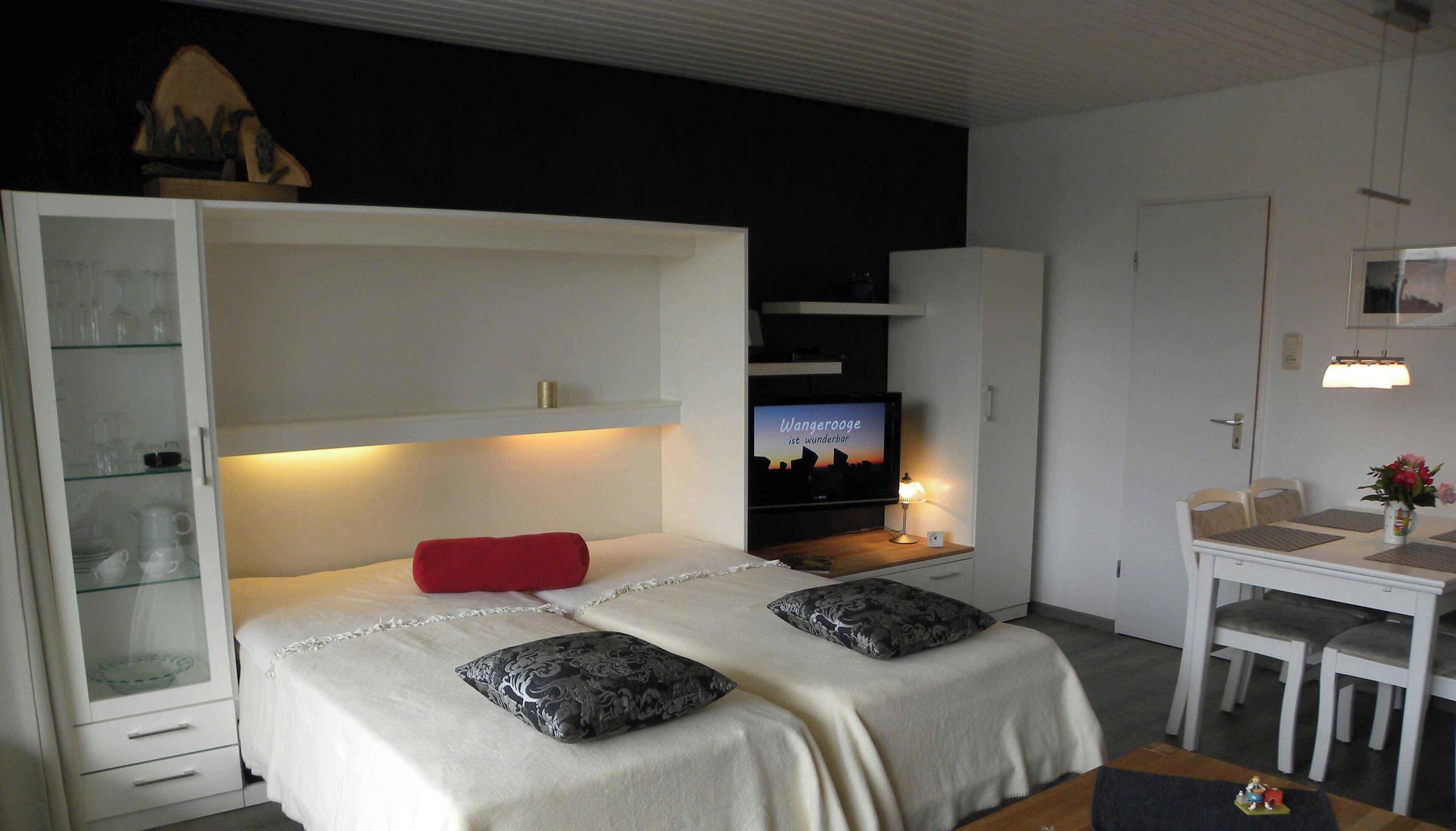 A bedroom with a bed, a TV, a desk, and a chair.