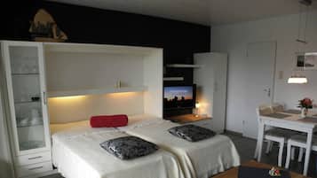 A bedroom with a bed, a TV, a desk, and a chair.