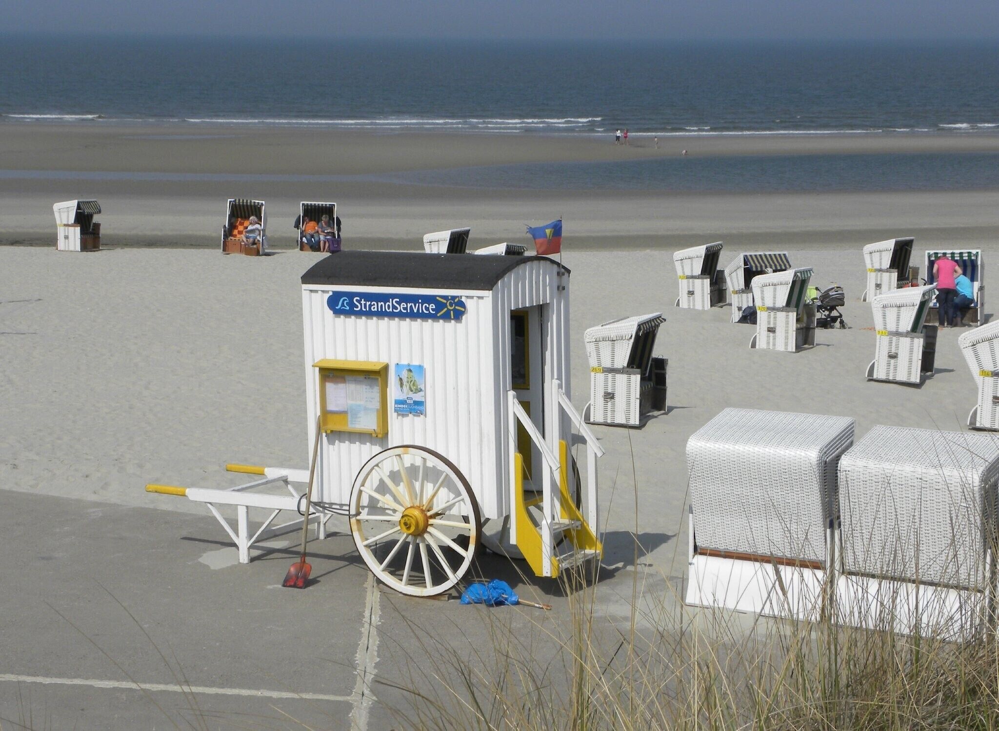 A beachside location with a small service station, a wheelbarrow, and beach chairs.