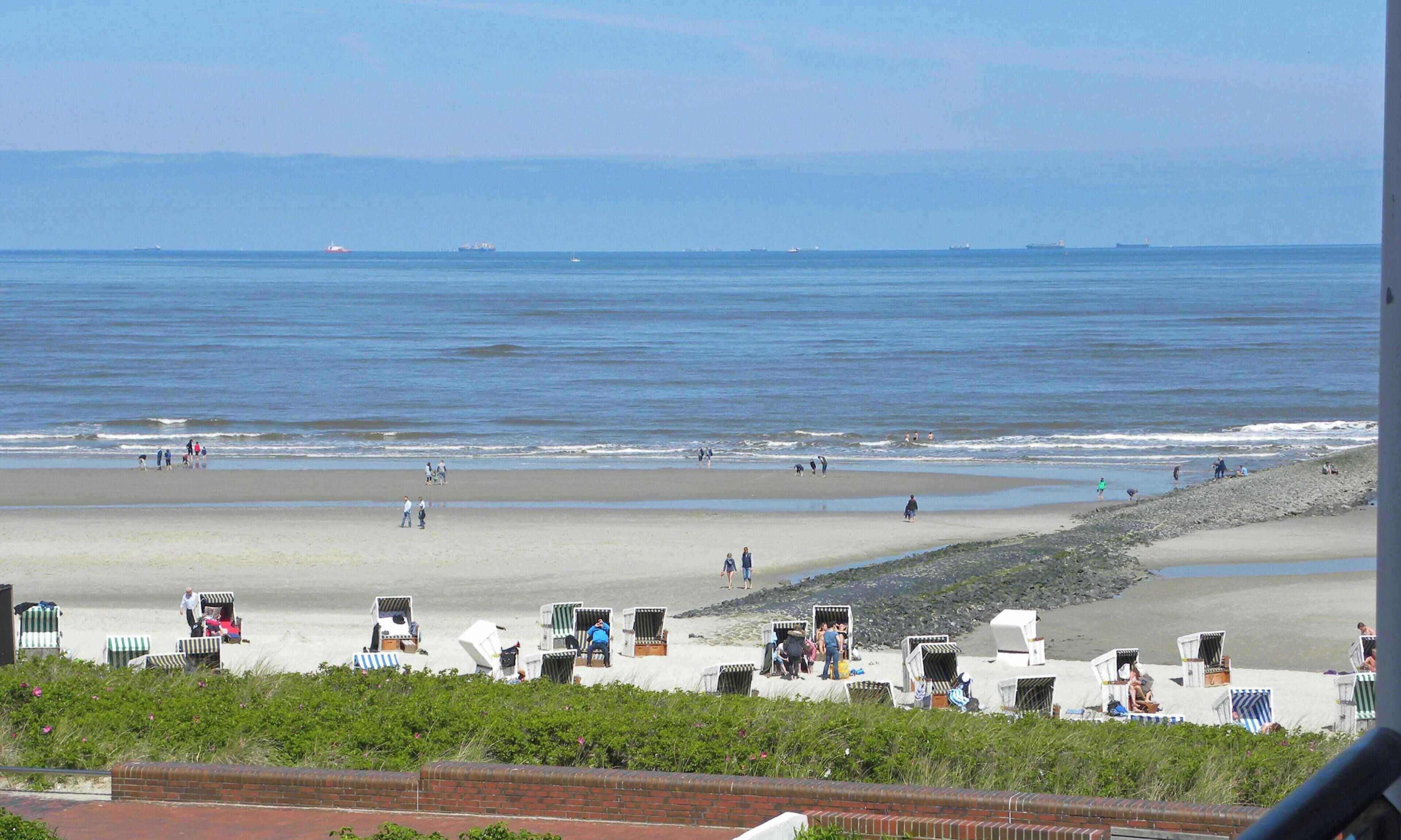 A beach with people, a sandy shore, and a view of the ocean.
