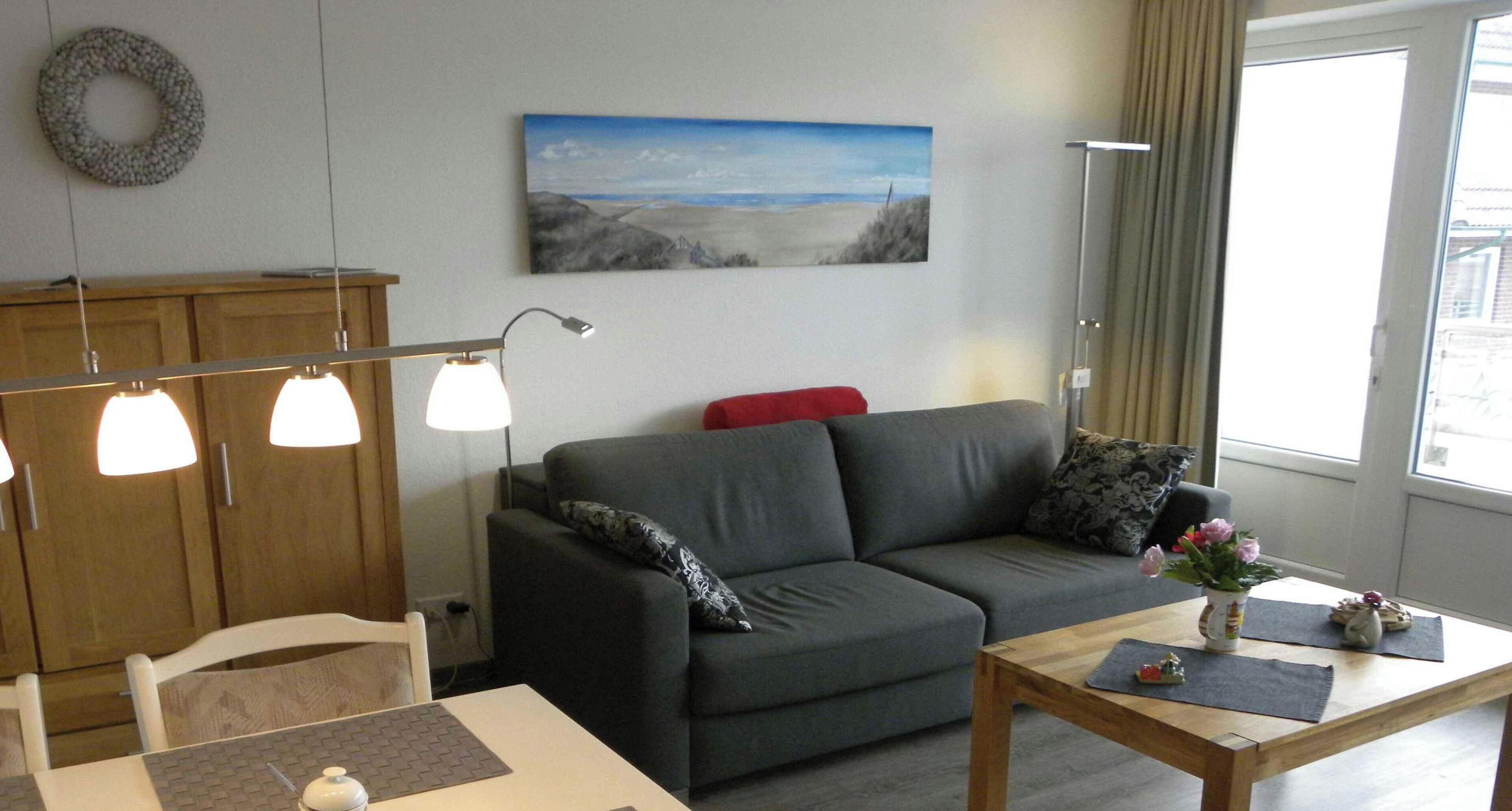 A living room with a sofa, a table, a lamp, and a painting on the wall.
