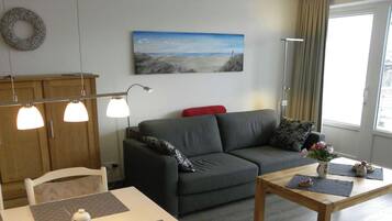 A living room with a sofa, a table, a lamp, and a painting on the wall.