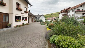 Una strada acciottolata fiancheggiata da edifici tradizionali, alcuni con balconi e fioriere.