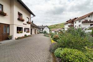 Une rue pavée bordée de bâtiments traditionnels, dont certains sont ornés de jardinières et de balcons.