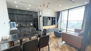 A modern kitchen with dark cabinets, a water dispenser, and a built-in oven. - Vinhomes Metropolis Ba Dinh - Apartment  (Hanoi)