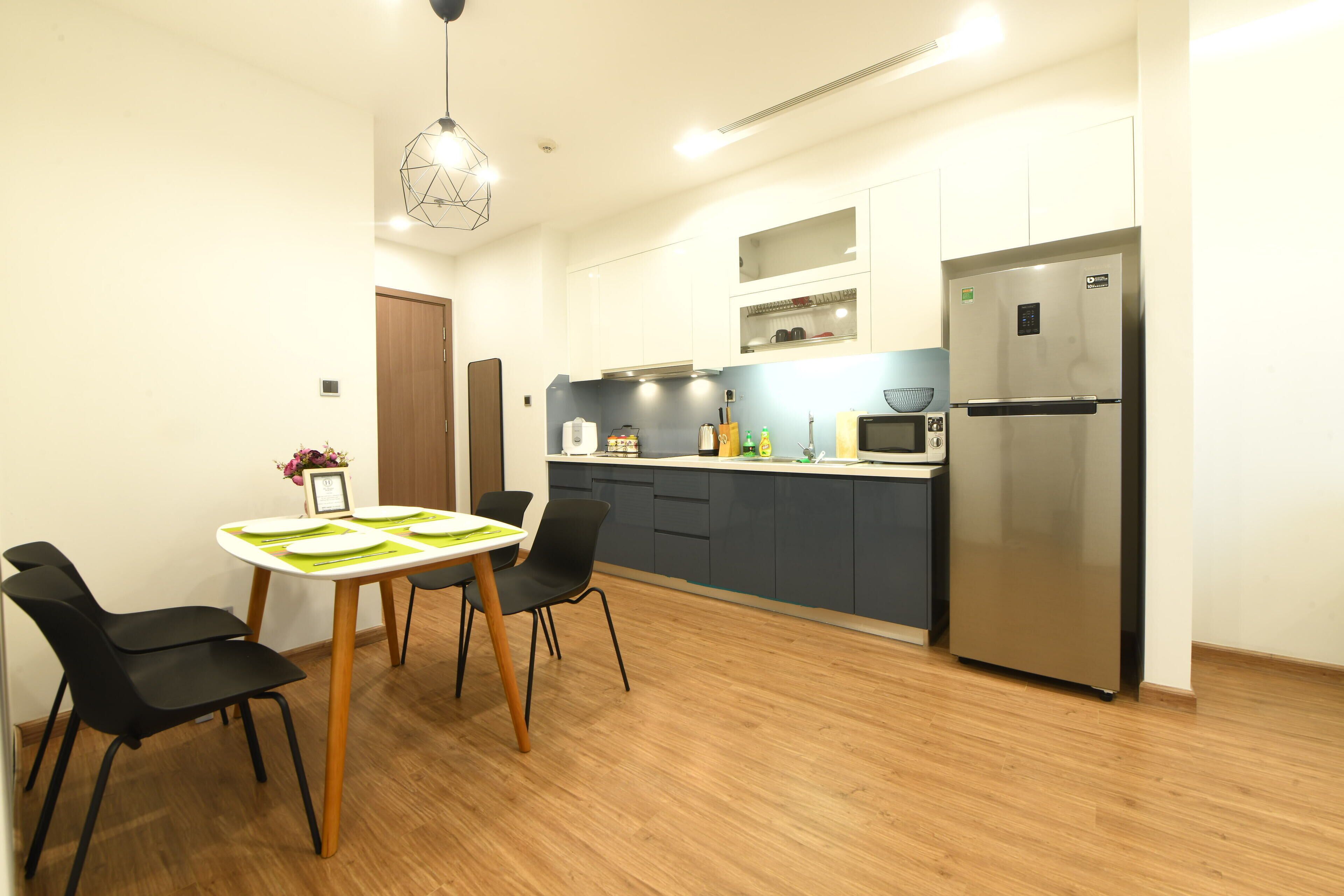 Een moderne keuken met een inbouwkoelkast, houten vloeren en een eethoek met een tafel en stoelen.