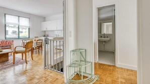 Eine geräumige Küche mit weißen Schränken, ein Essbereich mit Holztischen und -stühlen sowie ein Badezimmer mit Waschbecken und Spiegel.