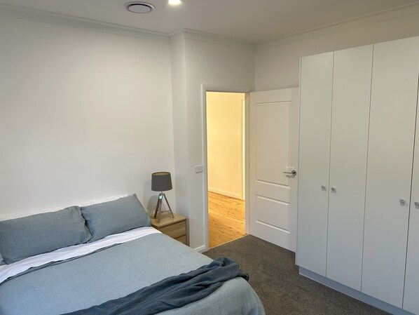 Un dormitorio con cama, lámpara de noche y armario.