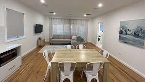 Un salon moderne avec un canapé, une table à manger et des chaises, un téléviseur à écran plat et un tableau accroché au mur.