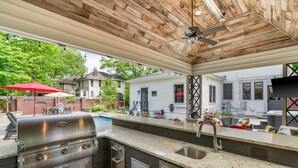 An outdoor kitchen with a grill, sink, and patio furniture. - 3BR Home | Private Pool & Spa | Games | Gazebo (Memphis)