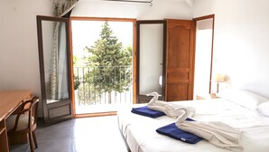 A hotel room with a bed, a desk, and a balcony with a view of trees. - La Novela - Calpe, Costa Blanca (Calpe)
