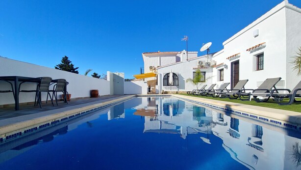 A swimming pool with lounge chairs and a table, surrounded by white buildings with tiled roofs. - La Novela - Calpe, Costa Blanca (Calpe)