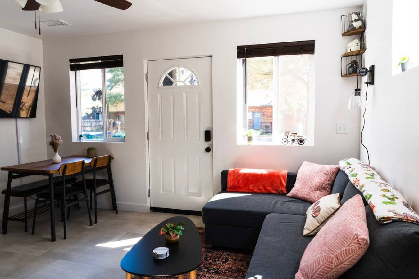 A living room with a sofa, a coffee table, a dining table with chairs, and a door.