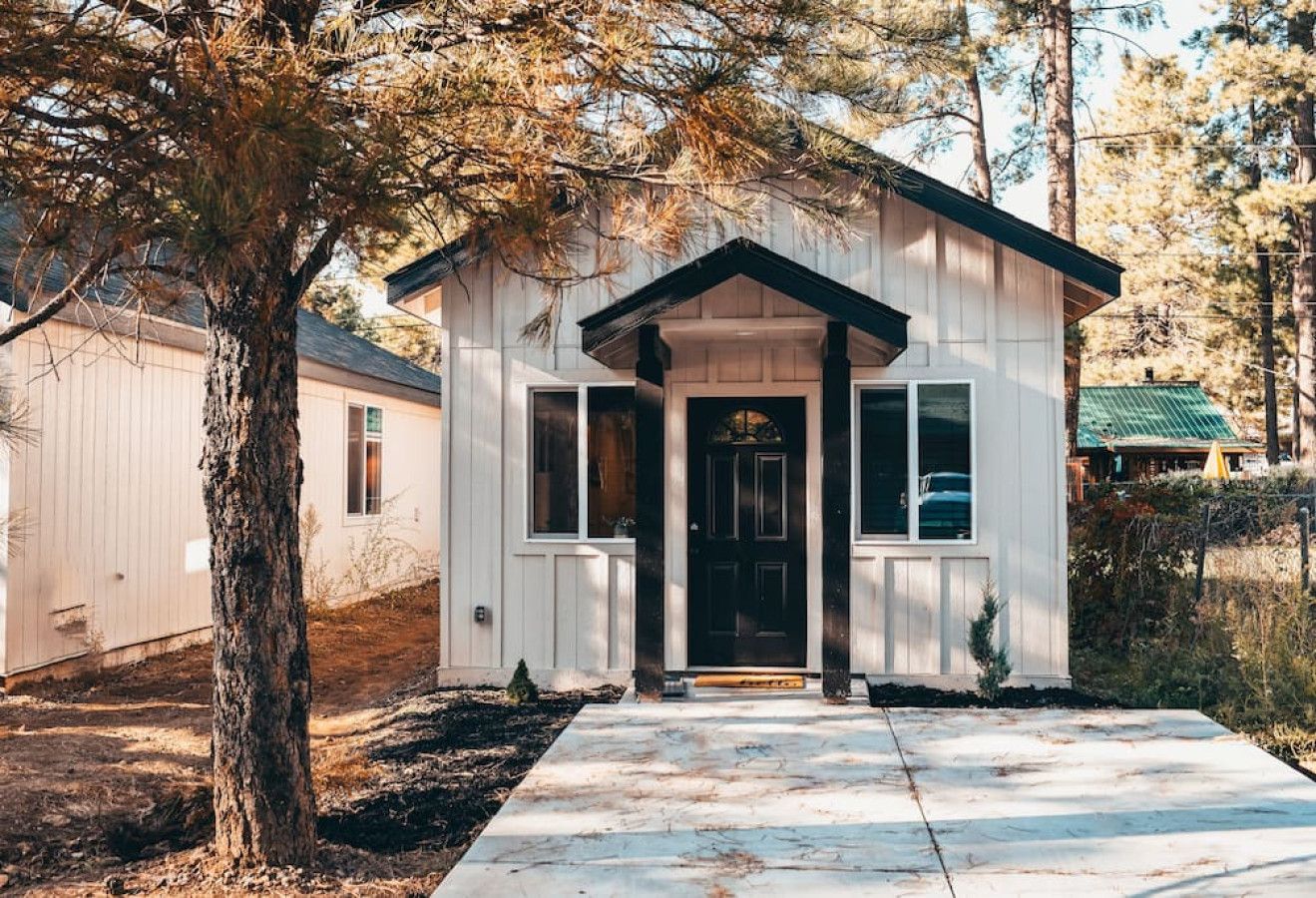 A small, single-story house with a front porch, a door, and windows.