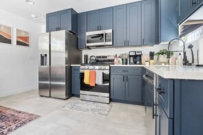 Una cucina moderna con elettrodomestici in acciaio inossidabile, mobili antracite e un piano di lavoro bianco.