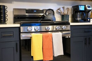 Una cocina con estufa, horno y cafetera.