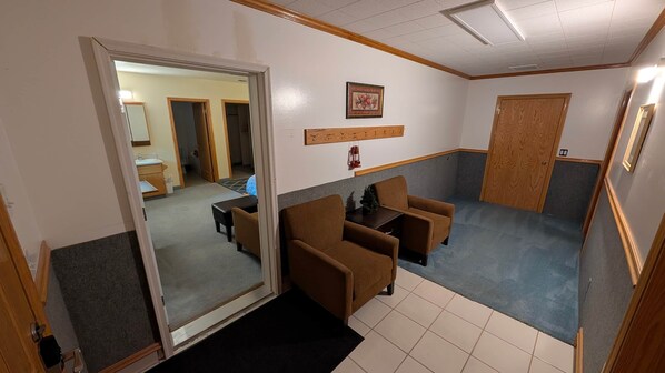 Habitación con un sofá, una mesita y un espejo. Se ve una puerta que da a otra habitación.
