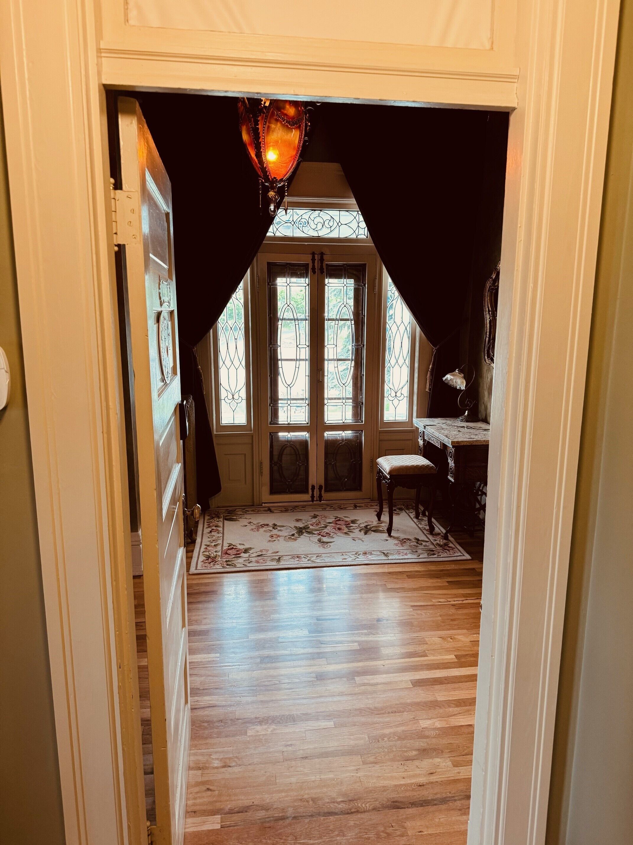 A hallway with a wooden floor, a chair, and a table with a vase.