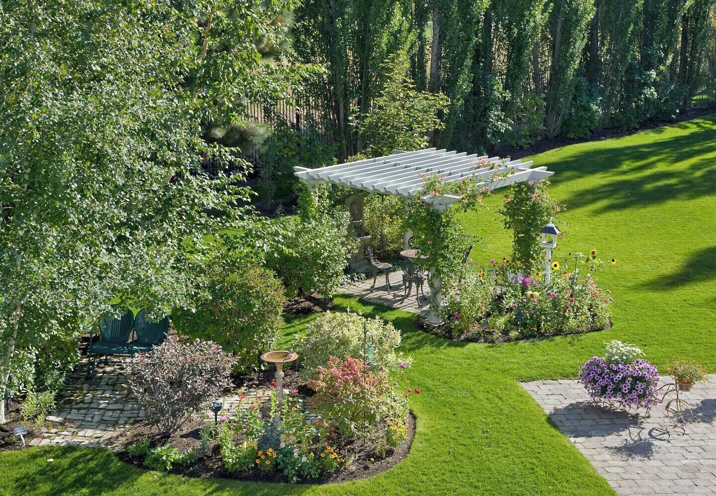 A garden with a gazebo, seating area, and various plants.