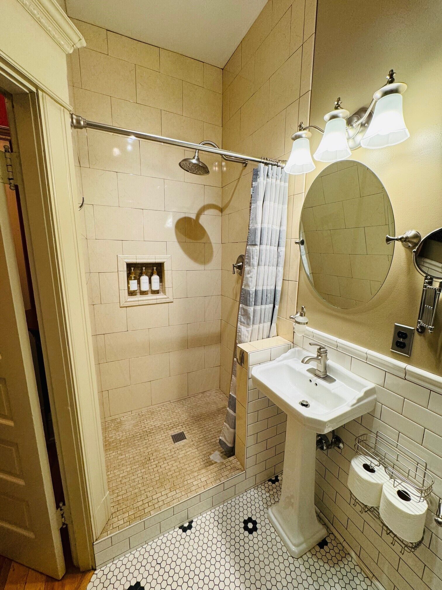Een badkamer met een douche, een wastafel en een spiegel.
