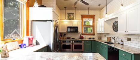 A kitchen with white cabinets, green countertops, a ceiling fan, and a window with blinds.