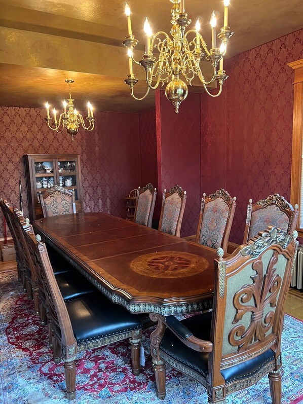 Un comedor formal con una larga mesa de madera, sillas ornamentadas y una araña.