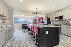 A modern kitchen with a central island, stainless steel appliances, and a view of mountains through large windows.