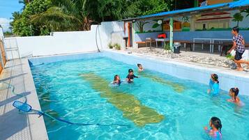 Guests can enjoy a refreshing swim in the pool surrounded by a mural-adorned seating area and a building with a rooftop balcony.
