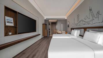 Un hotel moderno con una cama grande, un televisor montado en la pared y un mural con vista a la ciudad.