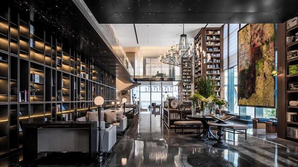 A spacious lobby with a polished marble floor, a central seating area, and tall bookshelves filled with books. - UrCove by Hyatt Shenzhen Shekou Cruise Center (Shenzhen)