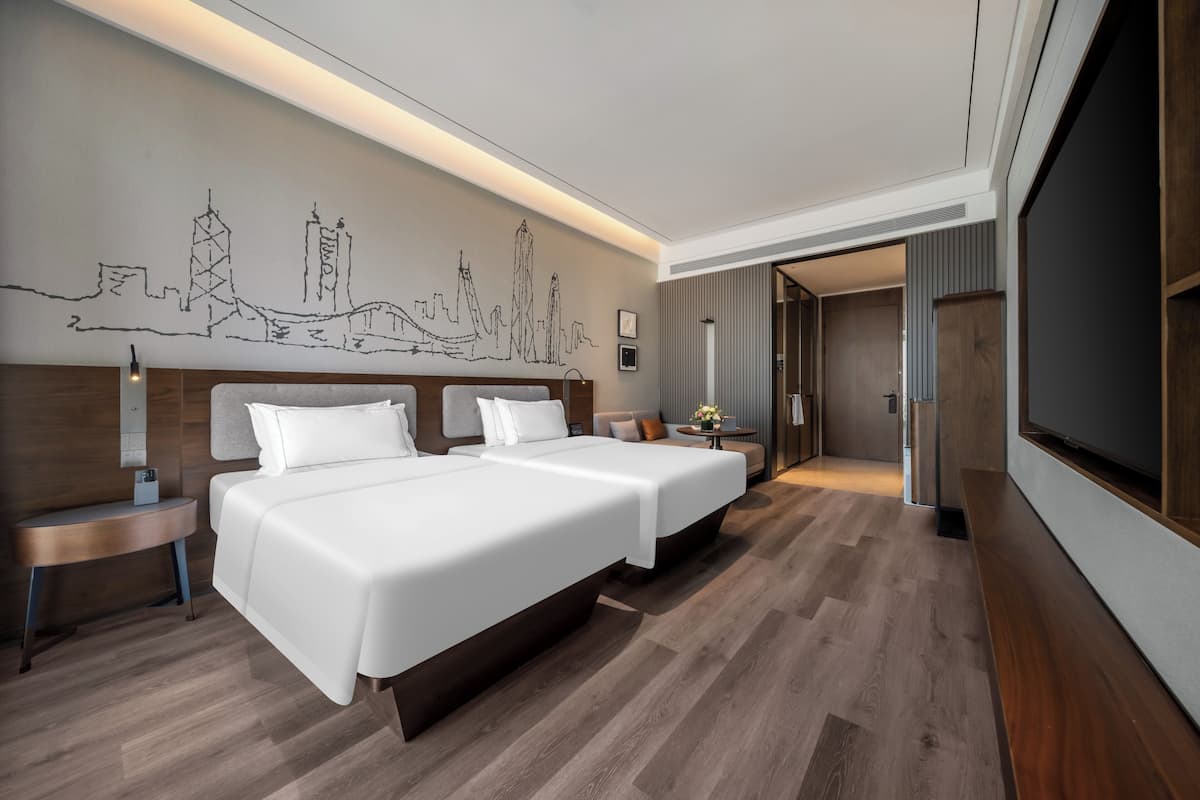 Une chambre d’hôtel avec deux lits, une fresque représentant un paysage urbain, un plancher en bois et un téléviseur.