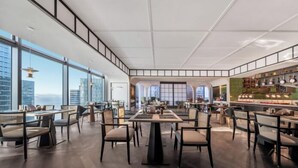 A modern restaurant with high ceilings, large windows, and a variety of seating arrangements. - UrCove by Hyatt Shenzhen Shekou Cruise Center (Shenzhen)