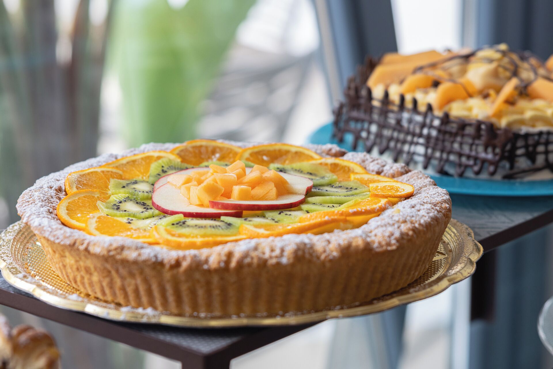 A dessert tray with a fruit-topped tart and a chocolate cake.
