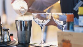 Un barista sirviendo una bebida en una copa tipo martini.