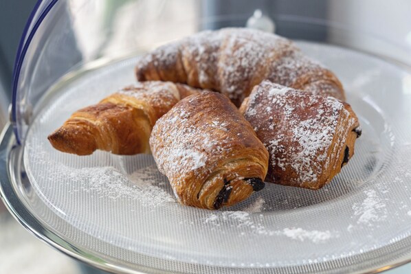 A glass plate with three pastries dusted with powdered sugar.