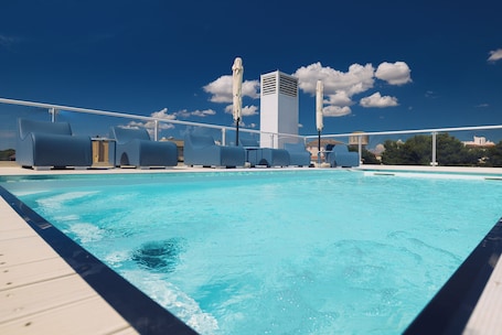 Una piscina al aire libre, sombrillas, sillones reclinables de piscina
