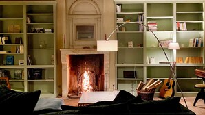 Una sala de estar acogedora con chimenea, estanterías, un sofá y una guitarra.