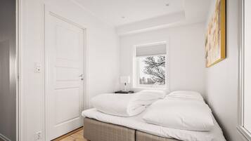 A bedroom with a bed, a bedside table, a window, and a door.