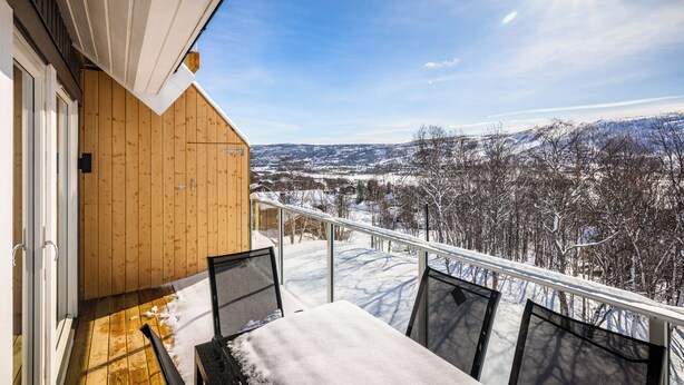 A wooden balcony with a table and chairs, overlooking a snowy landscape. - Gullstein (Hol)