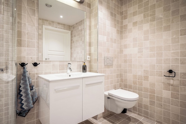 A bathroom with a white sink, a mirror, a toilet, and a towel rack. - Gullstein (Hol)