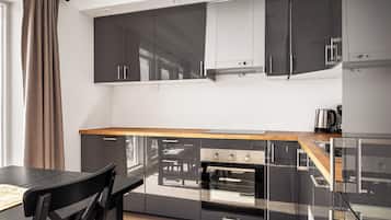 Una cocina moderna con armarios negros, encimera de madera y horno empotrado.