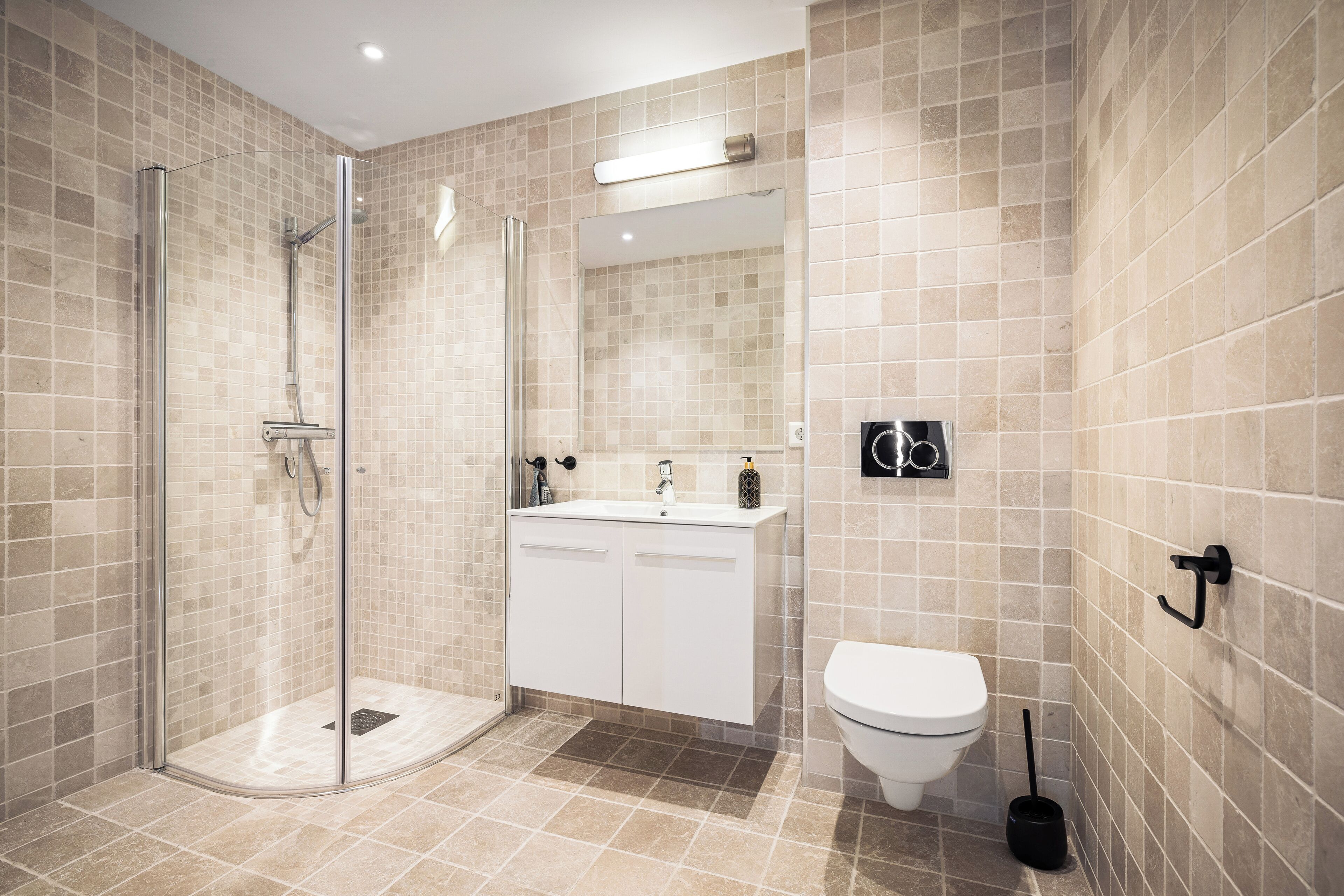 Un baño moderno con ducha de vidrio, lavamanos blanco y retrete.