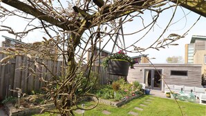 A backyard with a wooden fence, a garden with stepping stones, and a hanging flower pot.