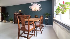 A dining area with a wooden table and chairs, a decorative wall piece, and potted plants.