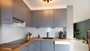 A compact kitchen with grey cabinets, a wooden countertop, and a built-in dishwasher.