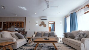 A modern living room with a sofa set, a coffee table, and a dining area with wooden furniture. - Seaside Bliss Vipingo (Kilifi)