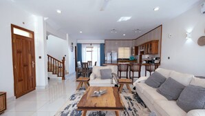 A spacious living room with a sofa, coffee table, and dining area. - Seaside Bliss Vipingo (Kilifi)