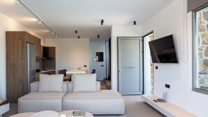 A modern living room with a sofa, a dining area, and a kitchen in the background. - Kōa Villa II, Stylish villa Near Beach by etouri (Heraklion)