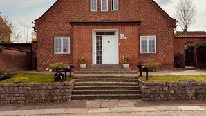 A red brick house with a white door and two windows on the upper floor. - Rent a full equipped basement in a Design house only 15min from city center. (Gentofte)