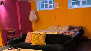 A living room with a sofa, a coffee table, a chair, and a rug. There is a window with a view of the outside. - Rent a full equipped basement in a Design house only 15min from city center. (Gentofte)
